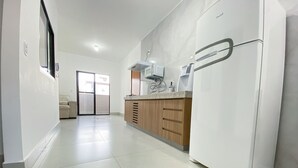 Una cucina moderna con frigorifero bianco, mobili in legno e pavimento piastrellato.