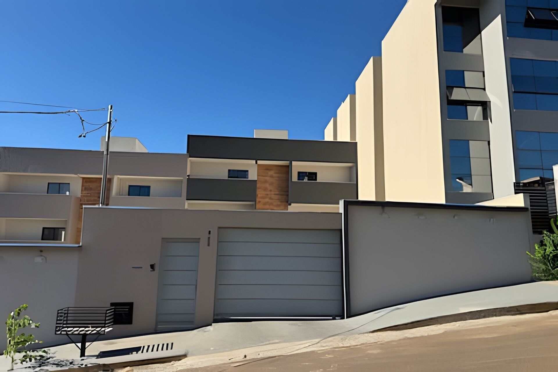 Een modern meerlaags gebouw met een garage deur, een kleine inkomhal en een zichtbaar balkon.