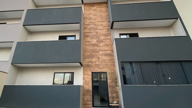 Un edificio a più piani con un ingresso centrale, ampie finestre e un’area di parcheggio antistante.
