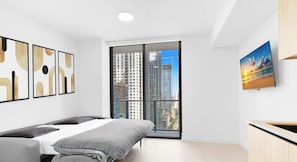 A modern bedroom with a bed, a window with a city view, and a painting on the wall. - Floor-to-Ceiling Light Chic Miami Studio (Miami)