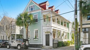A two-story house with a balcony, a garage, and a palm tree in front.