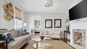A living room with a sofa, chairs, a round glass coffee table, a fireplace, and a TV.