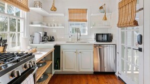 A modern kitchen with white cabinetry, a stainless steel dishwasher, a gas stove, and a microwave.