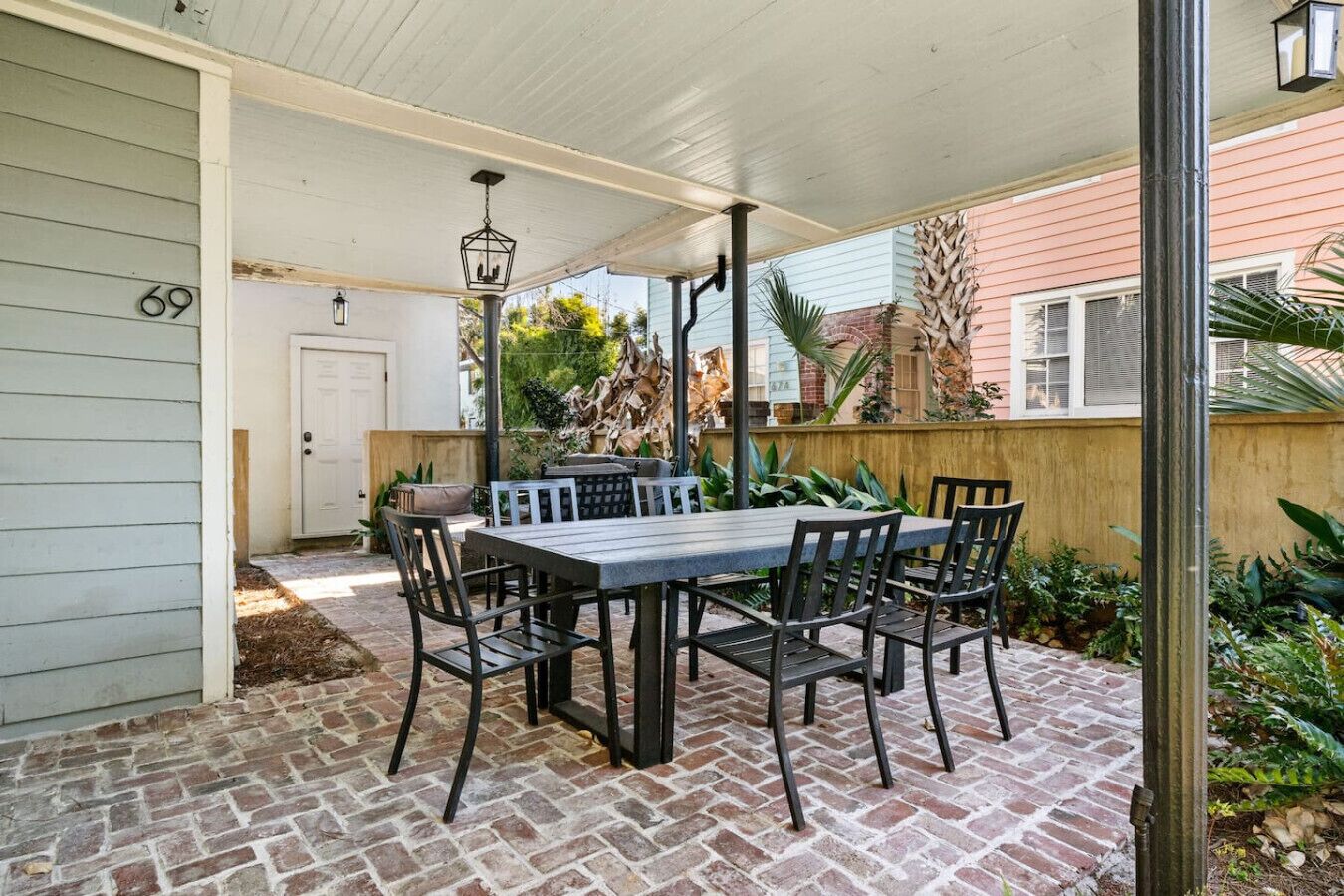 A covered patio with a table and chairs, a door, and a brick floor.
