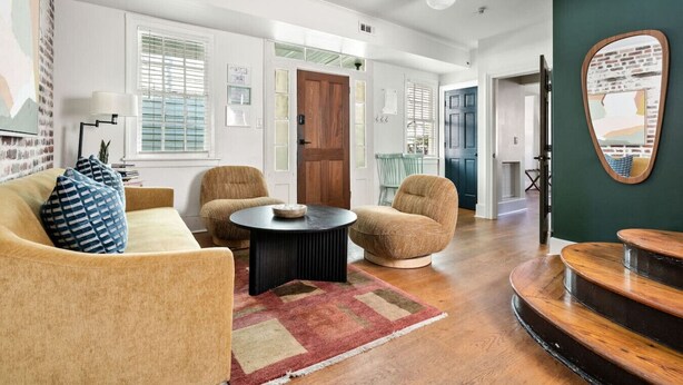Un amplio salón con un sofá, dos sillones, una mesa de centro y una escalera de madera.