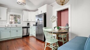 Una cocina moderna con armarios blancos, un refrigerador de acero inoxidable y un comedor con una mesa redonda y sillas.
