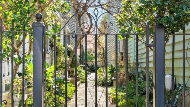 A gated garden with a stone pathway leading to a house. - Chic 2 Bedroom Spring St Retreat - Walk to King St (Charleston)