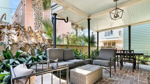 An outdoor patio with a sofa, chairs, and a table, surrounded by plants and a brick floor. - Chic 2 Bedroom Spring St Retreat - Walk to King St (Charleston)