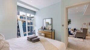 Een moderne hotelkamer met een bed, een dressoir, een spiegel en uitzicht op een stadsbeeld.