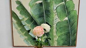 Une table à manger dressée avec de l’assiette blanche, des bols et un vase contenant une seule fleur.