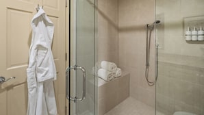 Ein Badezimmer mit Duschkabine, Handtuchhalter und Ablagefläche mit ordentlich gefalteten Handtüchern.