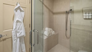 Ein Badezimmer mit Duschkabine, Handtuchhalter und Ablagefläche mit ordentlich gefalteten Handtüchern.