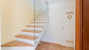 Eine Treppe mit Holzstufen und einem Glasgeländer, die zu einer weißen Tür mit einem runden Knopf führt.