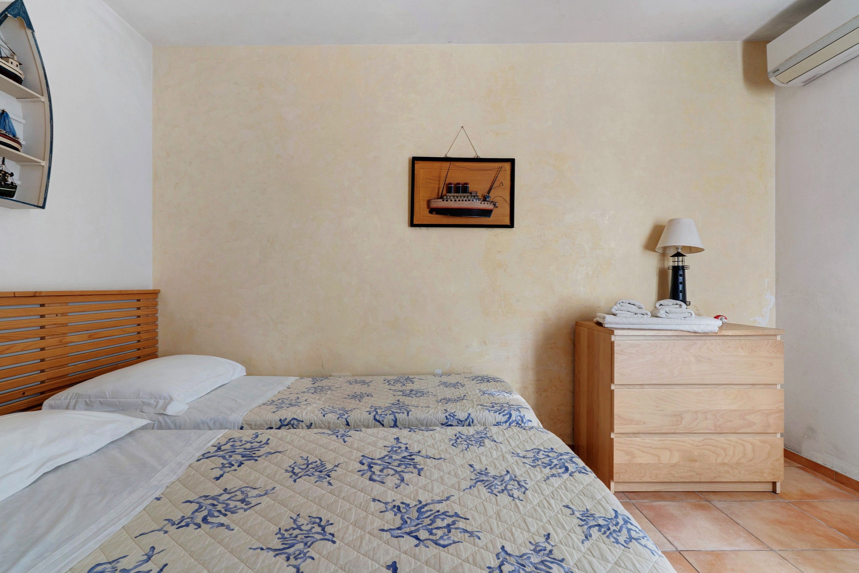 Un dormitorio con una cama, un aparador, un cuadro en la pared y una lámpara.