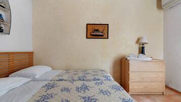 Un dormitorio con una cama, un aparador, un cuadro en la pared y una lámpara.