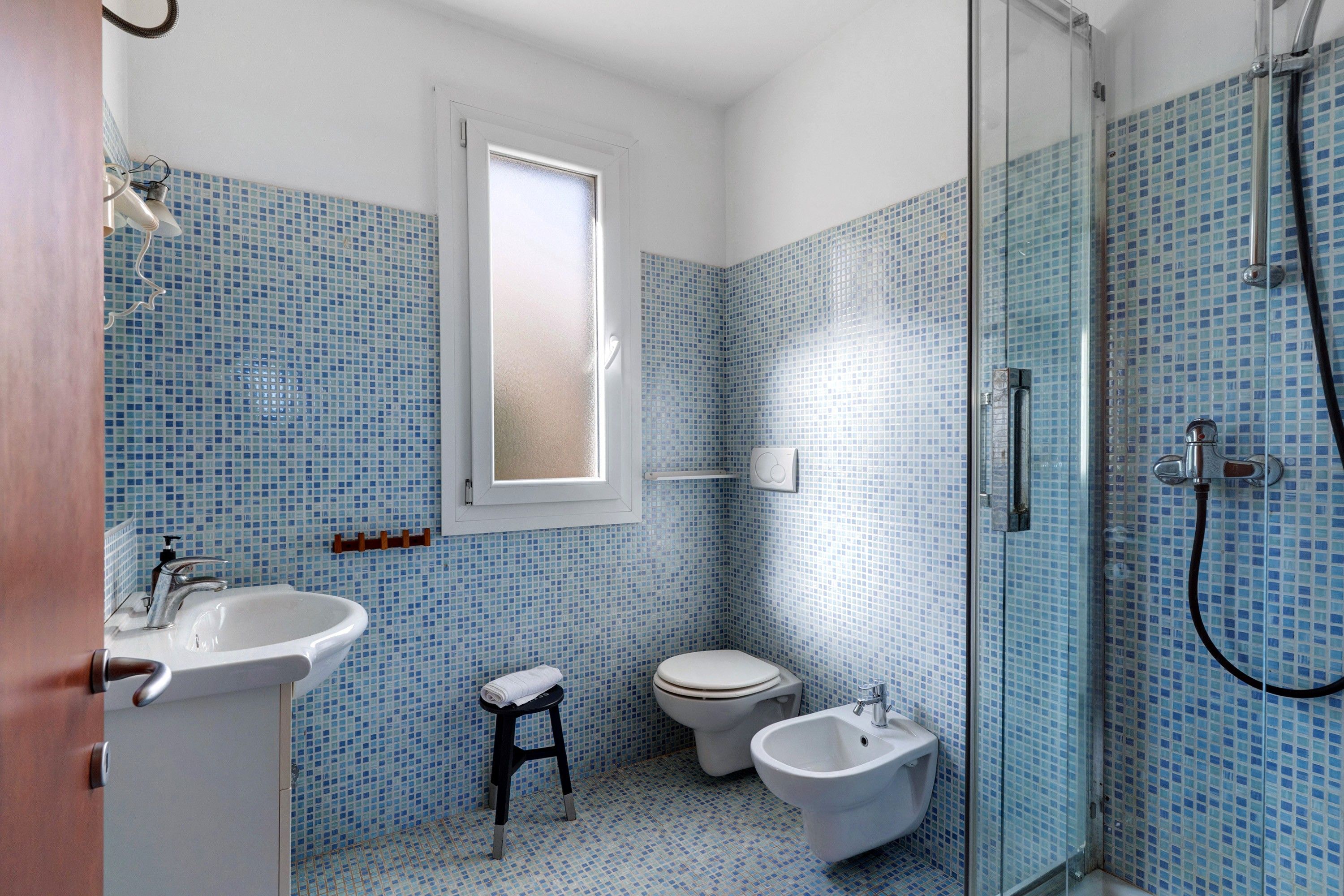 Une salle de bain équipée d’une douche, de toilettes, d’un bidet et d’un lavabo.
