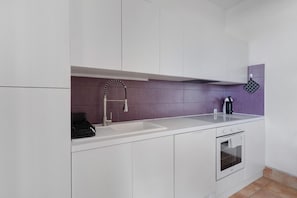 A modern kitchen with white cabinets, a stainless steel sink, and a built-in oven.