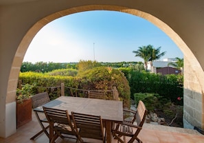 An outdoor patio with a wooden table and chairs, surrounded by a stone archway. - Quattro Colonne 3 Apartment with Sea View (Santa Maria al Bagno)