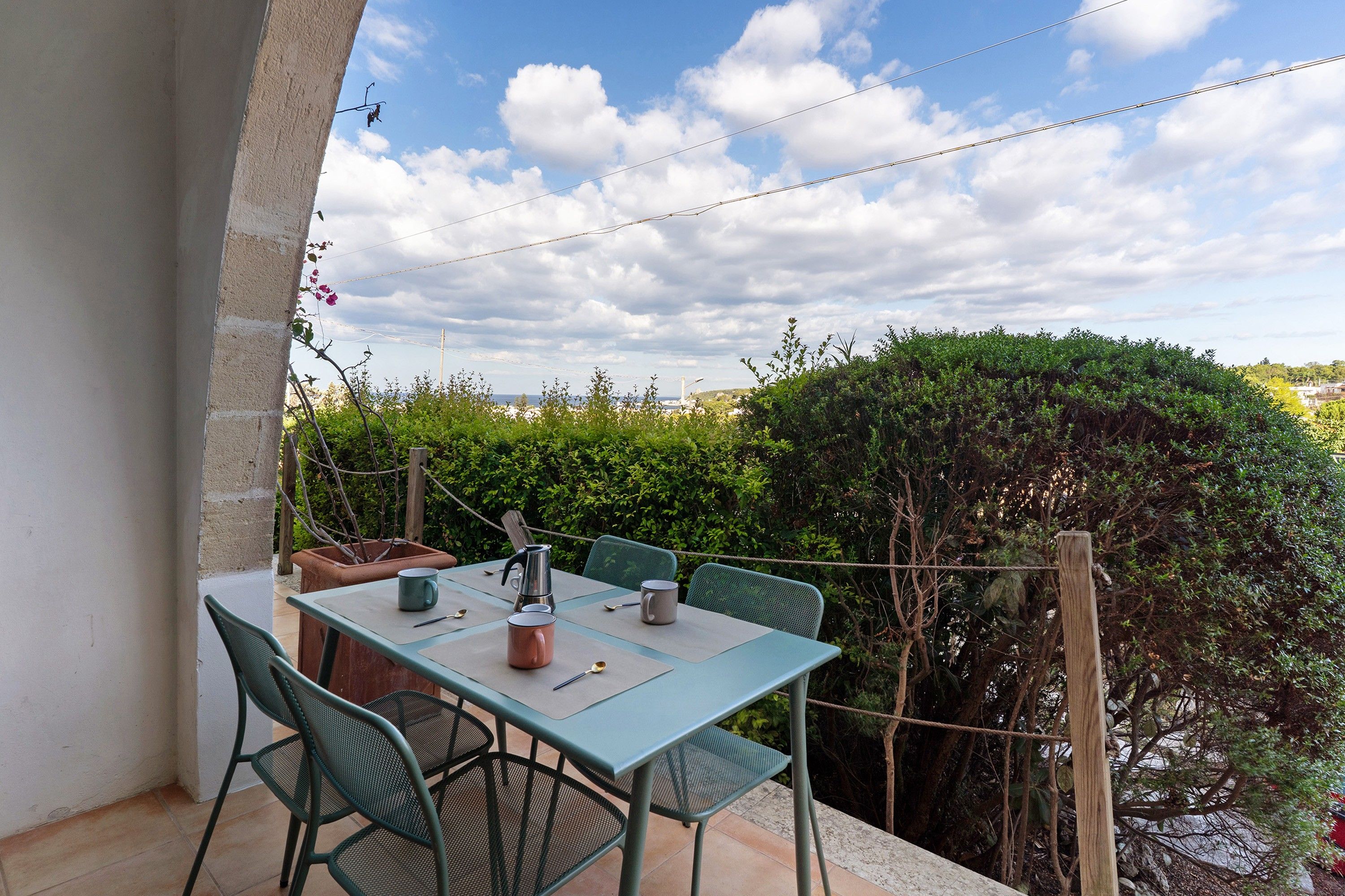 Ein Essbereich im Freien mit Tisch und Stühlen, Blick zum Himmel und umgebende Grünflächen.