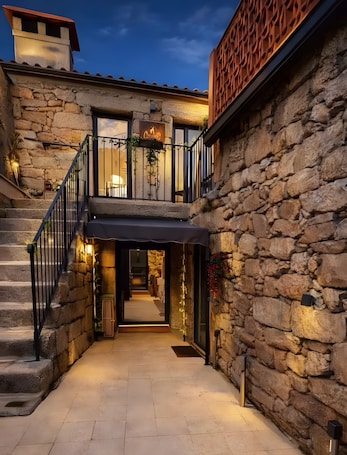 A stone building with a staircase leading to a balcony, a sign indicating a restaurant, and a view of the interior.