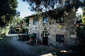 Un edificio de piedra con patio, mobiliario exterior y una puerta.