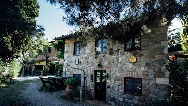 A stone building with a patio, outdoor seating, and a door.