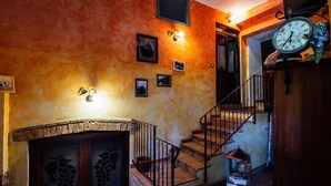 Una escalera con barandilla de hierro forjado, un reloj de pared y cuadros enmarcados.