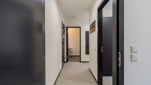 A modern hallway with a light-colored floor, dark walls, and a door leading to a bathroom. - Nena Apartments Moritzplatz by LESA (Berlin)