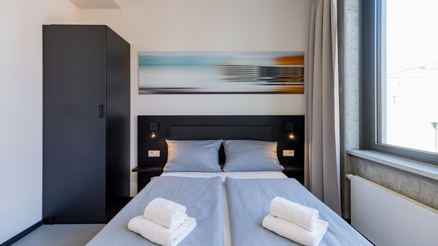 A modern hotel room with a large bed, two bedside tables, a wardrobe, and a window with curtains. - Nena Apartments Moritzplatz by LESA (Berlin)