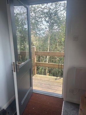 Una porta que dona a una terrassa de fusta amb vista a arbres.