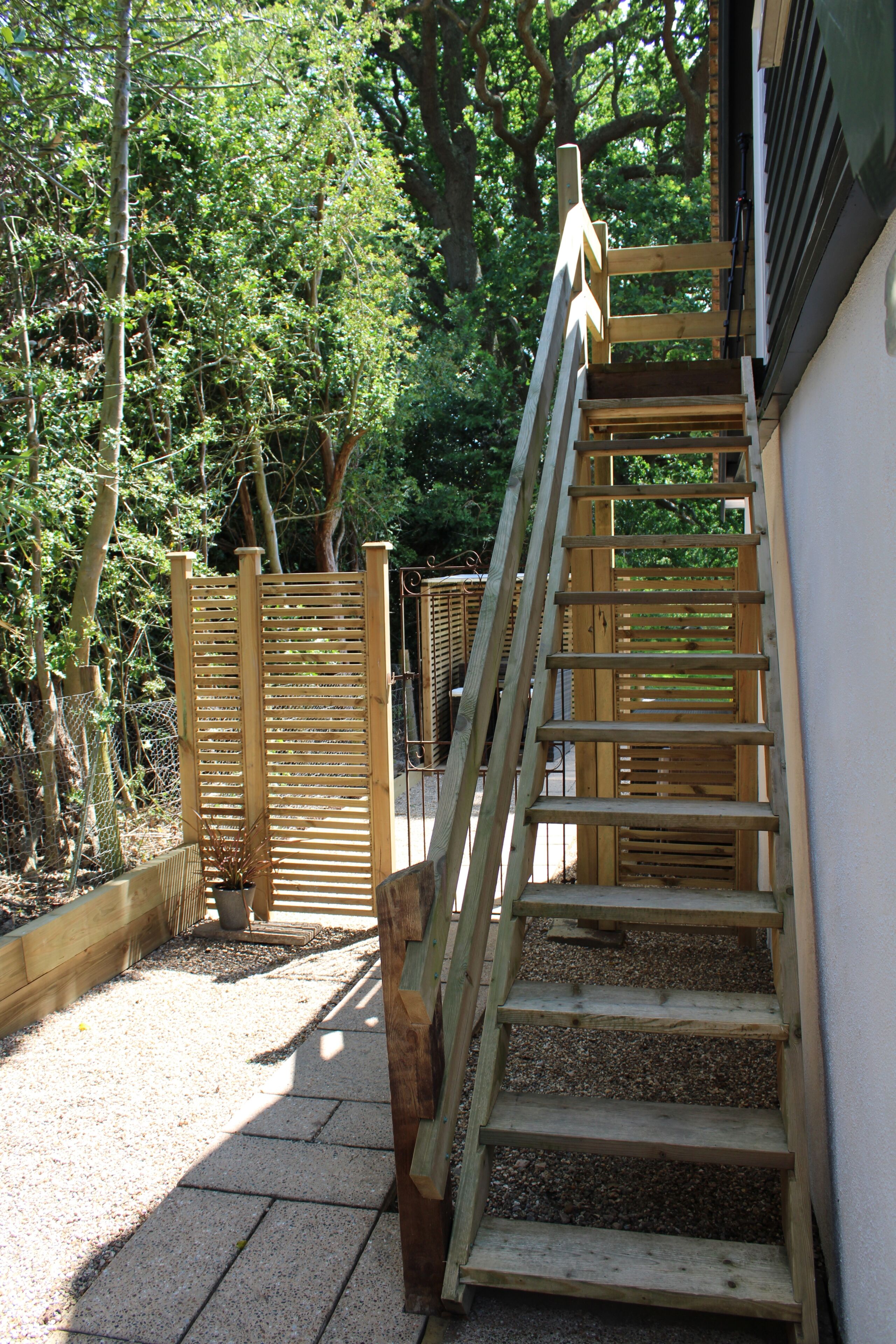 Una escalera de madera al aire libre que sube hacia un edificio.