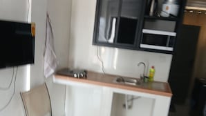 Keittiössä on mikroaaltouuni, pesuallas ja kaappeja. Siellä on myös tuoli ja pöytä.