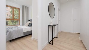 A modern bedroom with a bed, a window, a mirror, and a small table. - Comfortable Apartment | Parking | Remote Work (Warszawa)
