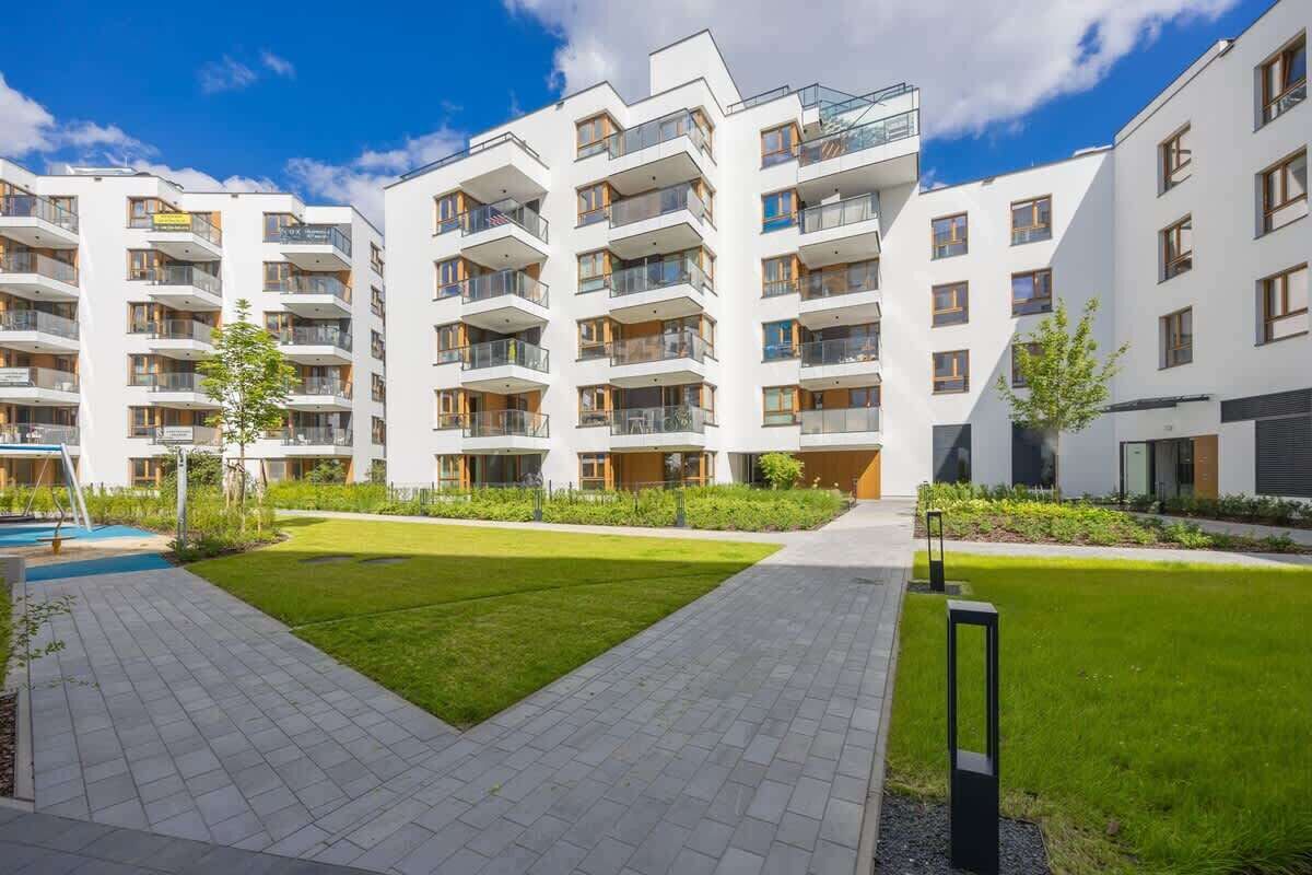 Un moderno complejo de apartamentos con varios balcones, un patio central y una piscina.