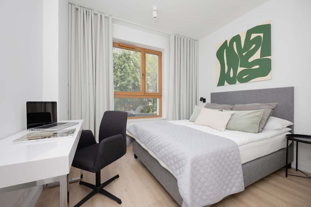 Une chambre d’hôtel moderne équipée d’un lit, d’un bureau, d’une chaise et d’une grande fenêtre.