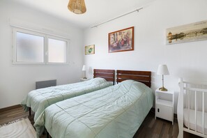 Un dormitorio con dos camas, cabeceros de madera, una mesita de noche, una lámpara y un cuadro en la pared.