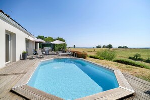 A swimming pool with a wooden deck and lounge chairs, surrounded by a grassy landscape and a clear sky. - Country House with Private Pool, Hot Tub, Wi-Fi and Air Conditioning in La Salvetat-Belmontet (La Salvetat-Belmontet)