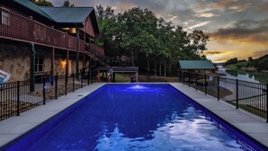 A rectangular swimming pool with a clear blue water surface, surrounded by a stone wall and metal railings. - Lakefront - Private Lake Retreat with INGROUND POOL! (Sevierville)