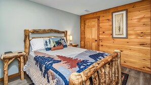 A bed with a wooden frame, a quilt, and two bedside tables with lamps. - Lakefront - Private Lake Retreat with INGROUND POOL! (Sevierville)