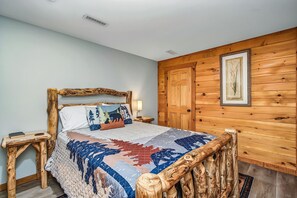 Een bed met houten frame, een sprei en twee nachtkastjes met lampen.