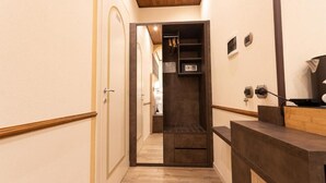 A hallway with a wooden floor, a coat closet, and a reception desk. - Antica Piacenza (Piacenza)