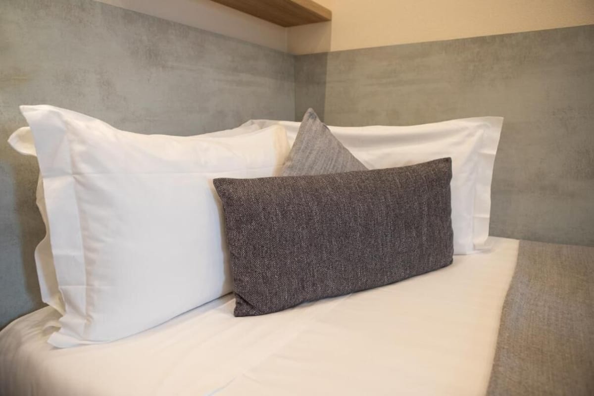 A bed with white and gray pillows, a gray textured pillow, and a wooden headboard.