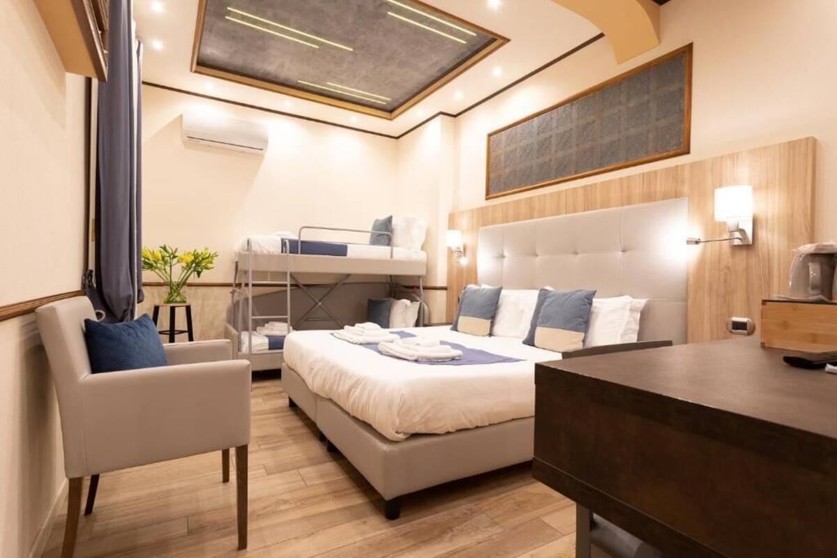 A modern hotel room with a bunk bed, a desk, a chair, and a large window.