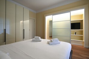 A bedroom with a large bed, a wardrobe, a television, and a sliding door closet. - Me too exclusive apartments - Calefati DB (Bari)