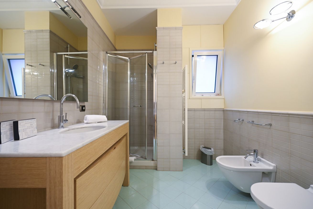 A modern bathroom with a shower, sink, and toilet.