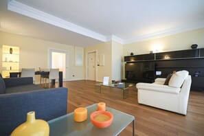 A modern living room with a sofa, a glass coffee table with candles, a white sofa, and a kitchen area in the background. - Me too exclusive apartments - Calefati DB (Bari)
