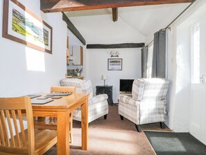 Ein gemütliches Wohnzimmer mit einem Holztisch, zwei karierten Sesseln, einem Kamin und einem Fernseher.