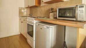 Uma cozinha com eletrodomésticos brancos, micro-ondas, fogão e geladeira.