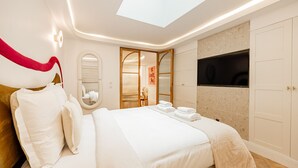 Une chambre d’hôtel moderne dotée d’un grand lit, d’une lucarne, d’une télévision et d’une armoire.