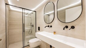 Une salle de bain moderne avec une douche à parois de verre, un lavabo blanc et deux miroirs fixés au mur.